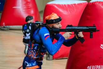 Боец LASERWAR целится из-за красного надувного укрытия.